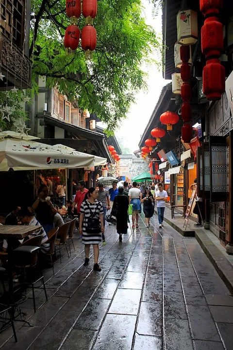 A narrow wet street lined with shops and red lanterns
