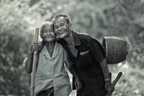 An older couple smiling together with baskets on their backs