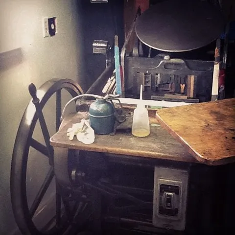 Oil containers on the wooden bed of an old printing press