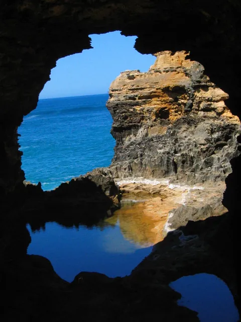 The sea and a rock pool seen through a dark cave opening