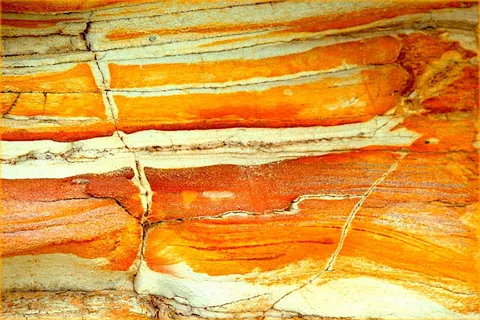 Close-up of orange, red and white bands in layered rock