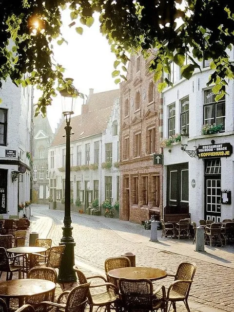 Outdoor cafe tables on a quiet street lined with brick buildings