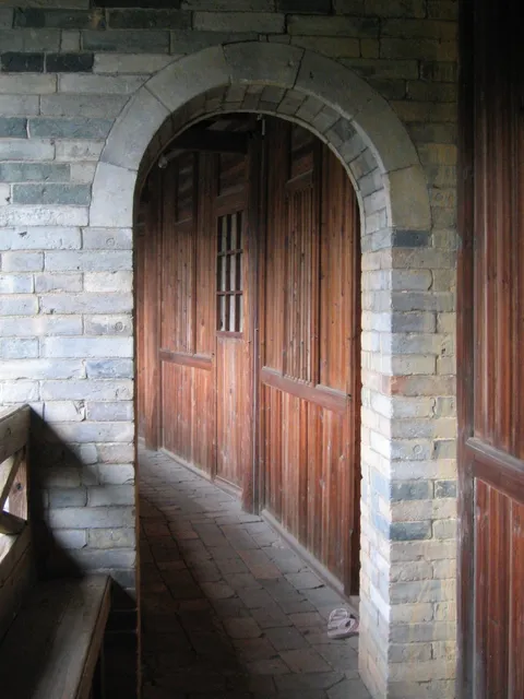 A wooden door in a stone archway along an interior gallery