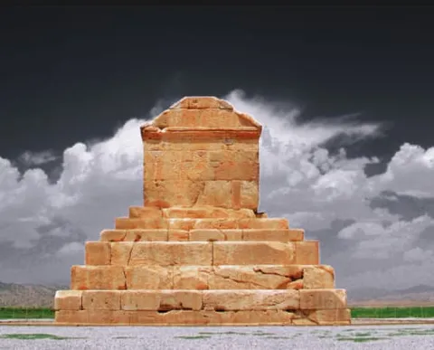 A stepped stone monument under a dark sky with white clouds