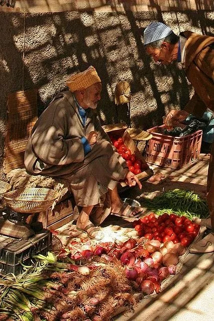 A vendor sitting behind an assortment of vegetables at a market stall