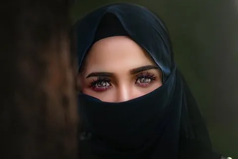 A woman in a black headscarf and face veil, only her eyes visible