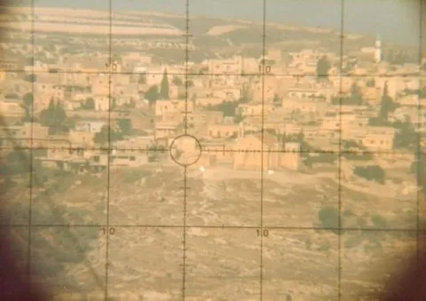 A town viewed through the crosshairs of an optical sight