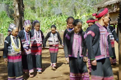 A group of men and women in embroidered black clothing walking in a circle