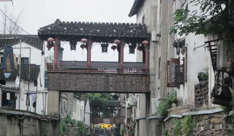A covered wooden bridge between white-walled buildings