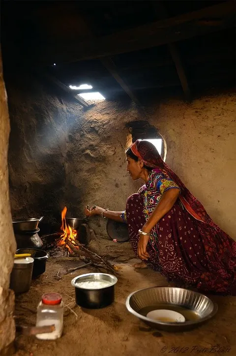 A woman cooking beside pots in a smoky kitchen