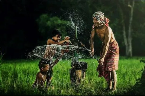 Two people splashing water at each other in a green field