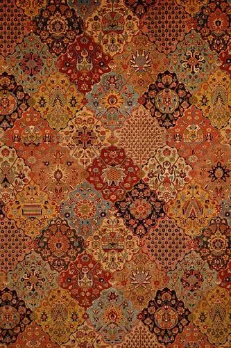 Close-up of a richly patterned carpet in red and gold tones