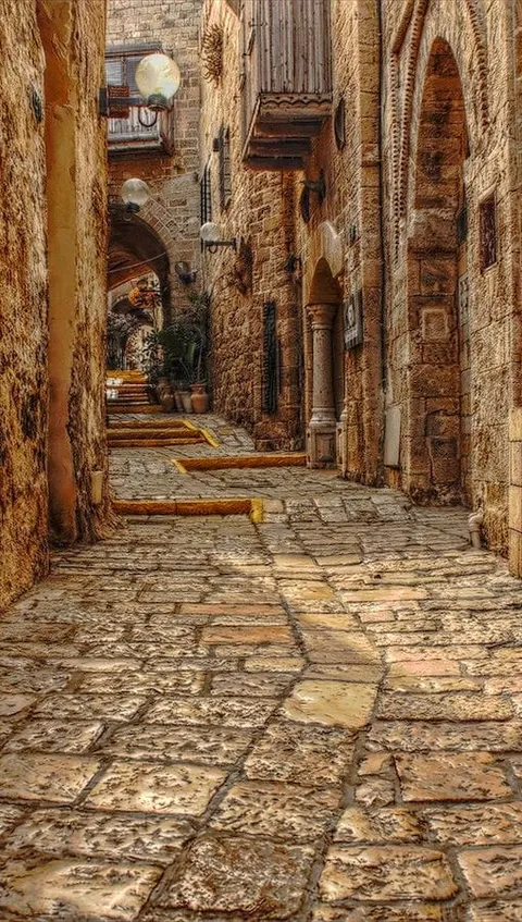 A narrow stone-paved alley between old buildings