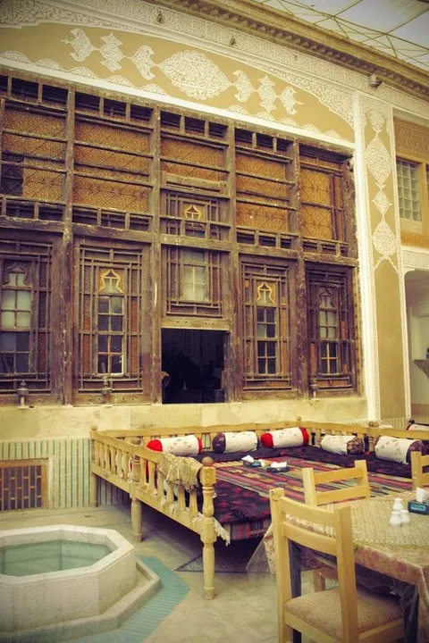 A courtyard with tables and chairs beneath ornate wooden windows
