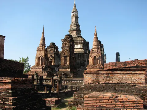Tall weathered temple spires rising above low brick ruins