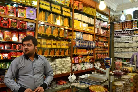 A shopkeeper standing before shelves of jars and containers
