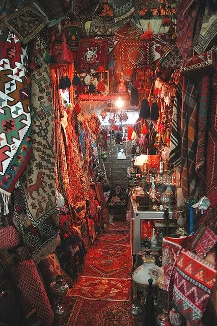 A narrow market passage lined with hanging carpets