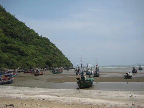 Fishing boats resting on a beach below a green hillside