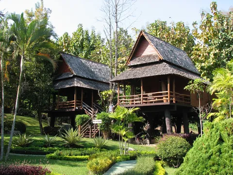Raised wooden houses surrounded by trees and garden plants