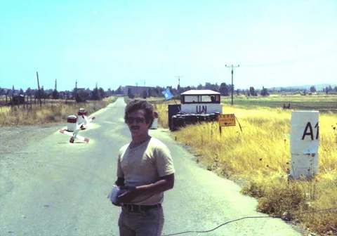 A man standing beside a road near a checkpoint