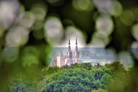 Distant church towers seen through a gap in green leaves