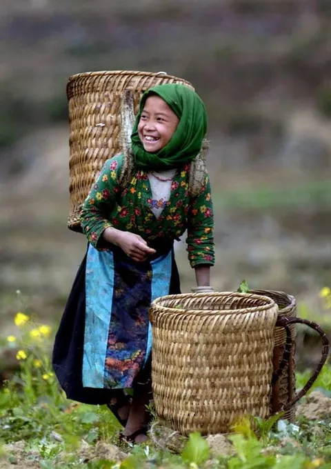 A smiling woman standing outdoors beside a large woven basket