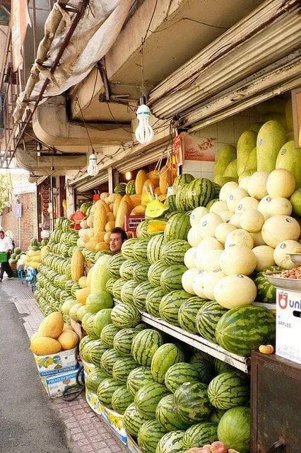 Watermelons and pale melons stacked along a market shopfront