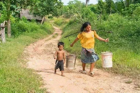 Children carrying buckets along a dirt path