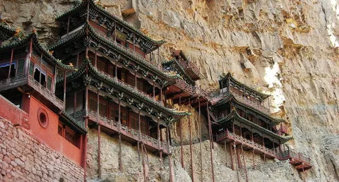 Wooden temple buildings built along the face of a steep rock cliff