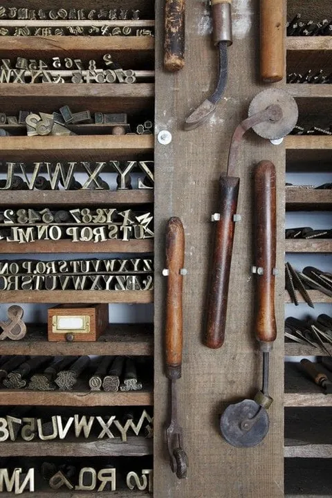 Metal letters in wooden compartments beside hand tools