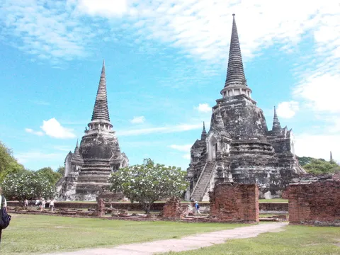 Two old brick stupas standing in a grassy temple enclosure