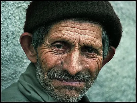 An older man with a grey stubbled beard and dark knitted hat