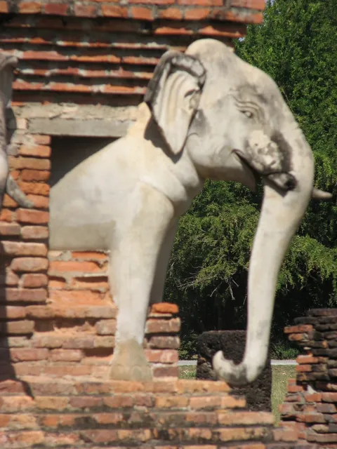 A stone elephant sculpture projecting from an old brick wall