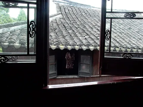 View through an open window toward tiled roofs and a small courtyard