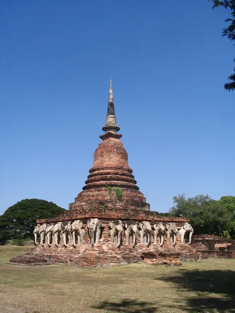 An old brick stupa surrounded by a ring of stone elephant sculptures