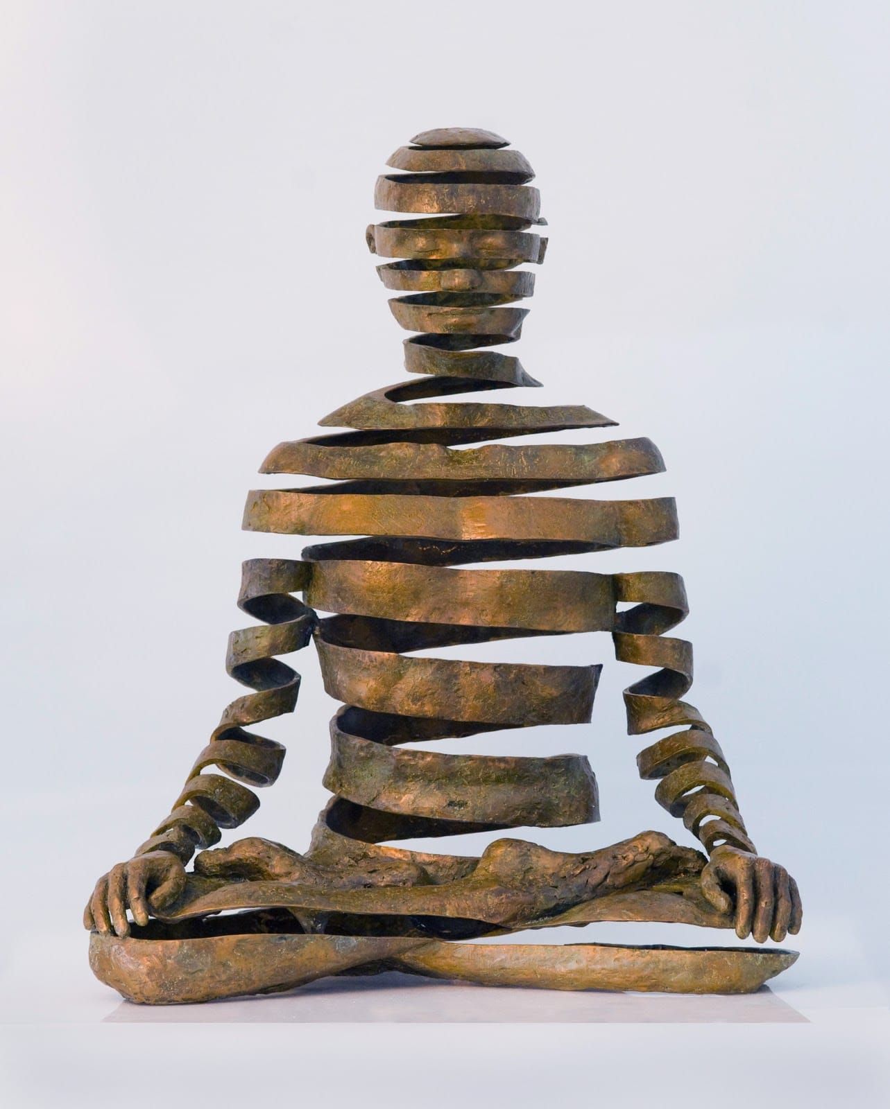 Bronze sculpture of a seated meditating figure made of separated horizontal bands